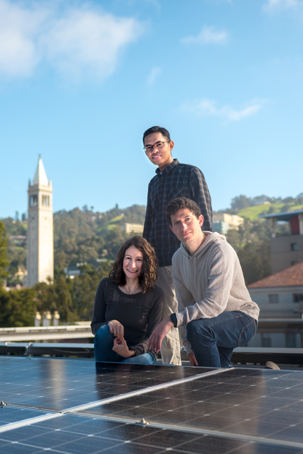 A group of people stand together on a roof in front of a solar array