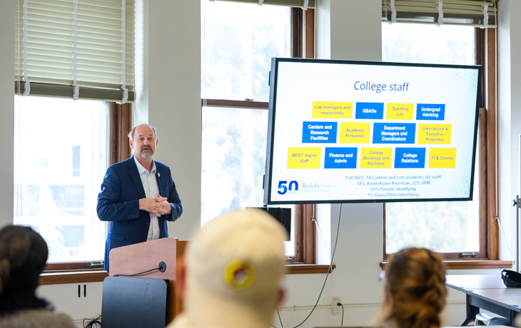 A person speaking with slides in front of a group.