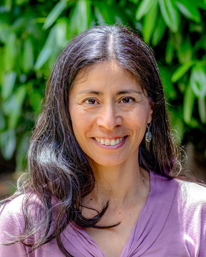 Susana Matias smiling in front of leaves.