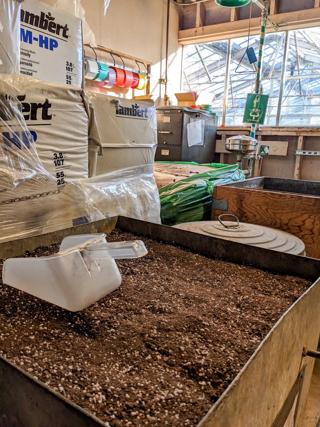 Soil bin with bags of soil behind it.
