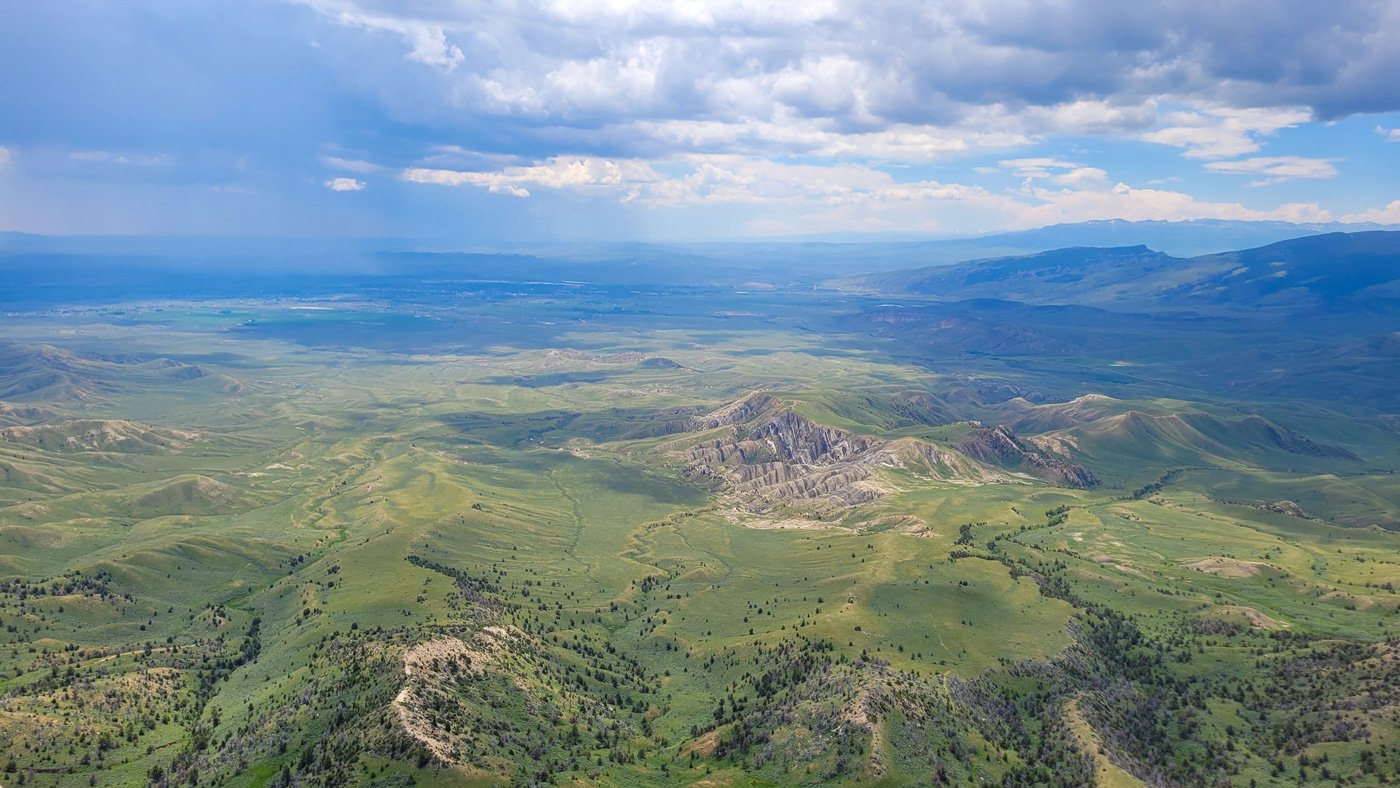 A landscape photo of a green valley and mountains with a blue sky