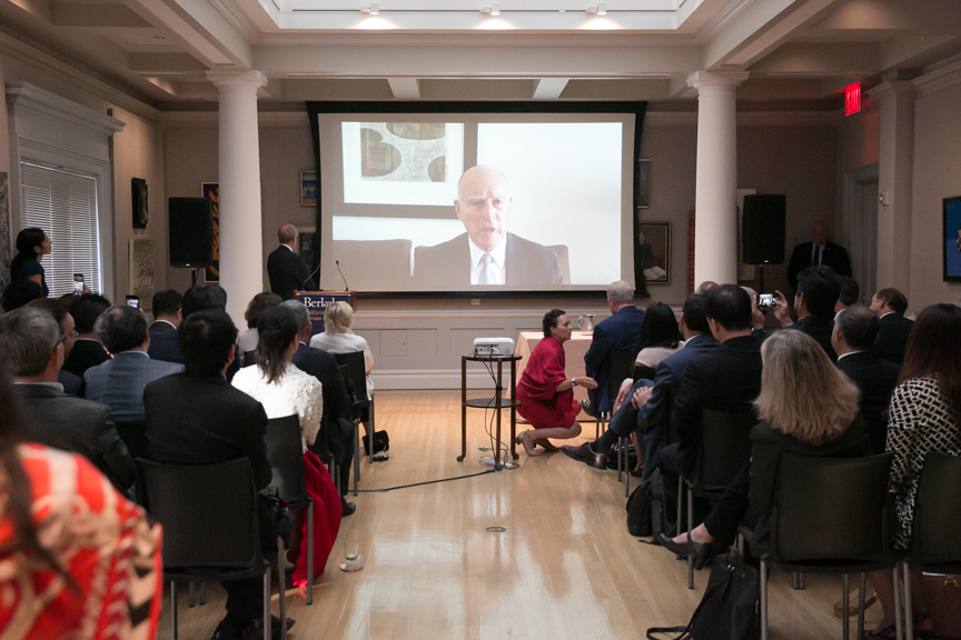 Jerry Brown addressing an audience on a video screen