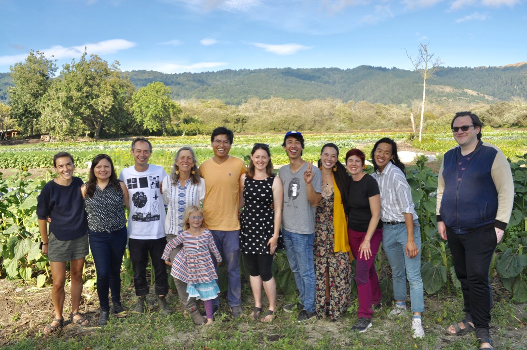 Group of people standing in a field on a farm.