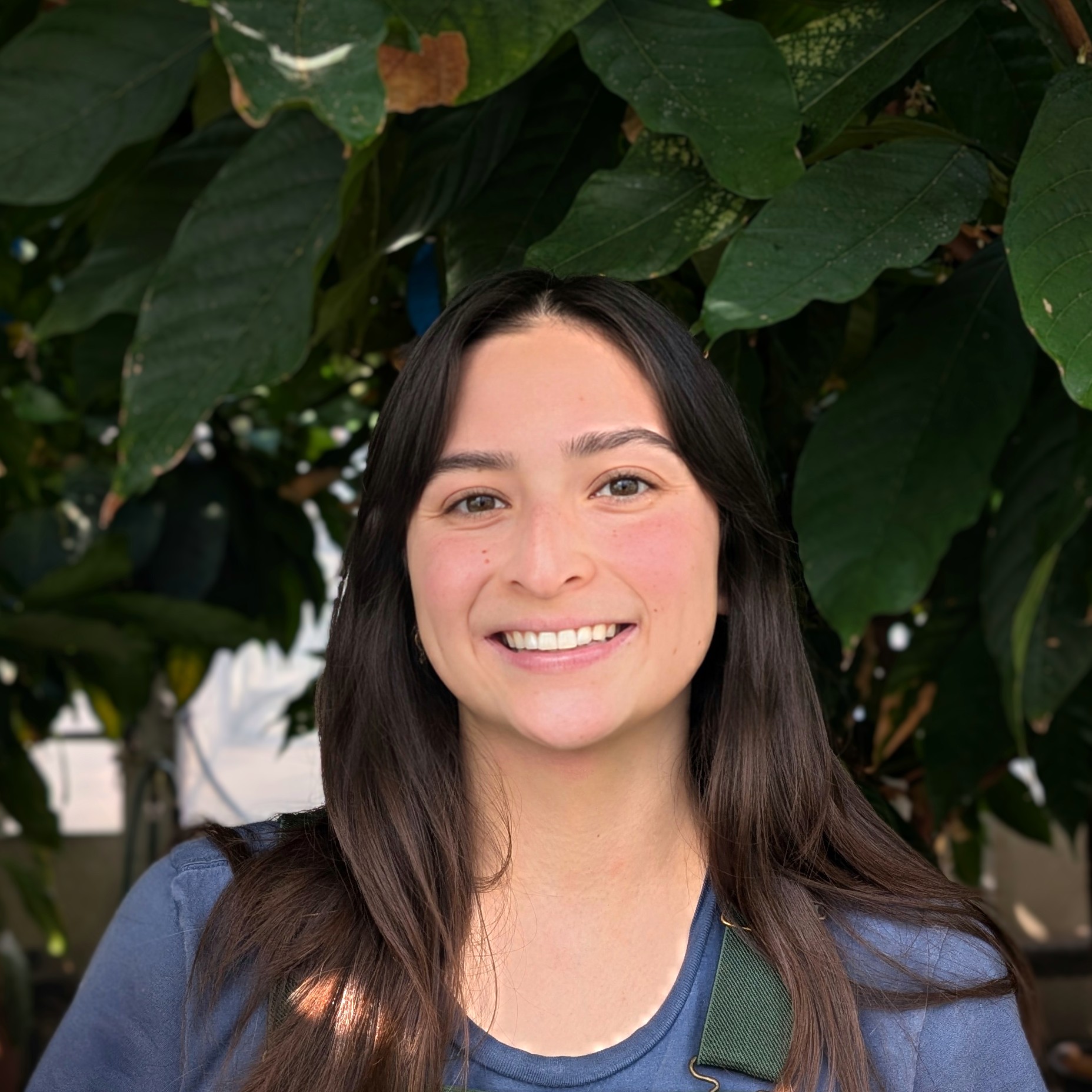 Headshot of a person with plants behind them.