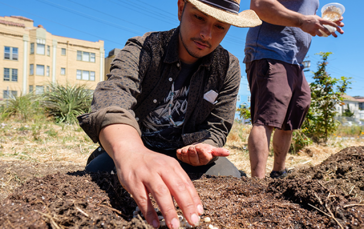 A man sowing seeds into the dirt.