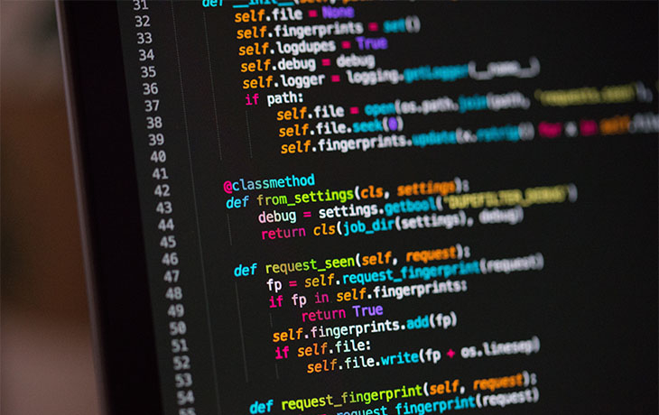 Multicolored strings of a programming are visible on a computer screen.