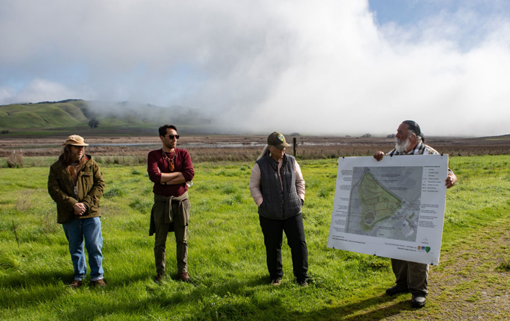 A photo of several people standing in a green field, with one person holding a map.