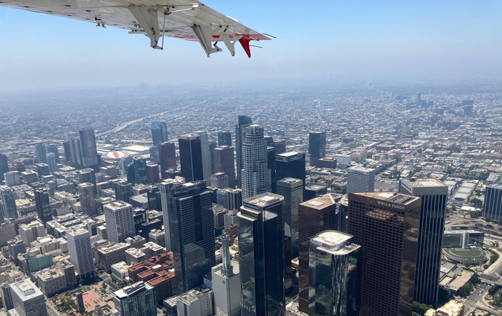 A photo that shows an aerial view of the buildings in downtown Los Angeles along with a partial view of a plane wing.