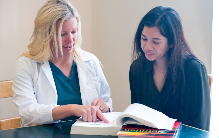 An instructor, Susie and a student reading a book.