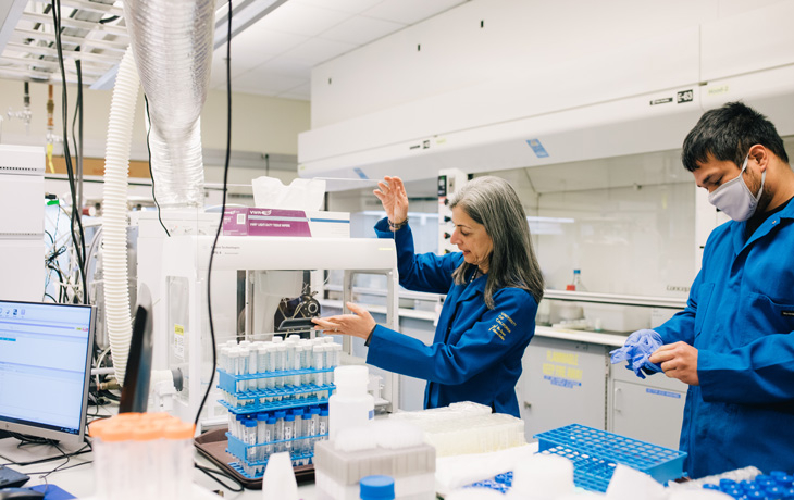 Sabeeha Merchant working in a lab with an assistant to the right.