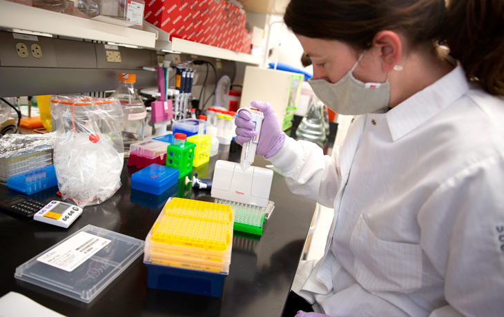 A woman uses a piece of scientific equipment in a lab environment.