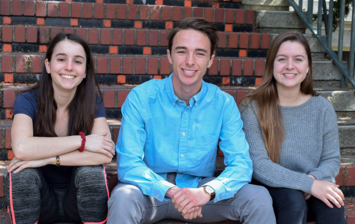 Three students sit on the front steps of Giannini Hall