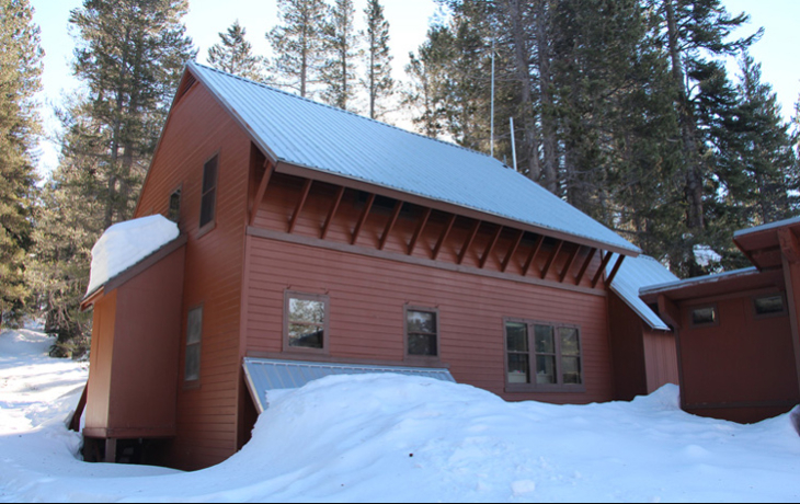 Red colored house somewhere very snowy in a forest.
