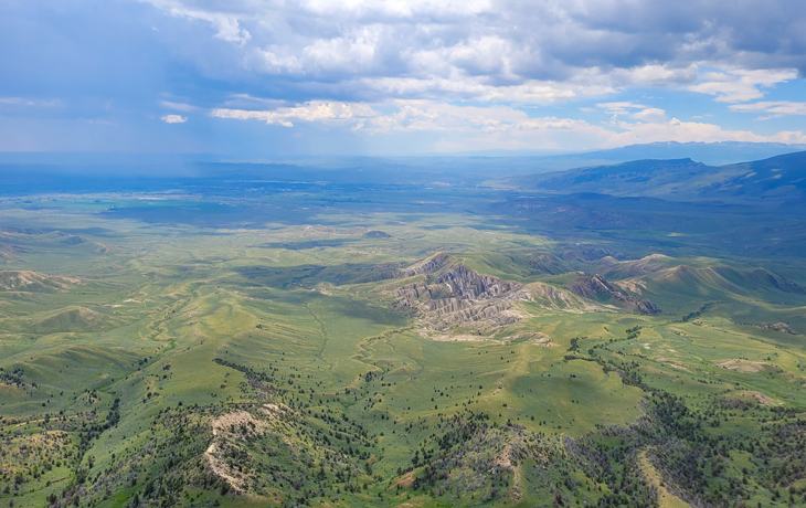 A landscape photo of a green valley and mountains with a blue sky