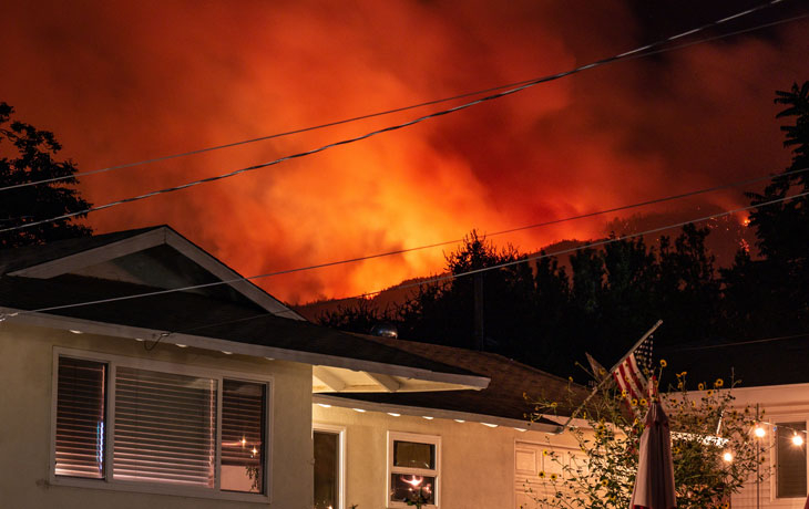 Image of a wildfire behind a residential house