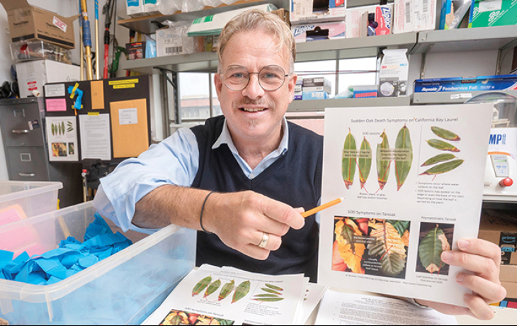 Matteo Garbelotto pointing at a paper with infected tree leaves