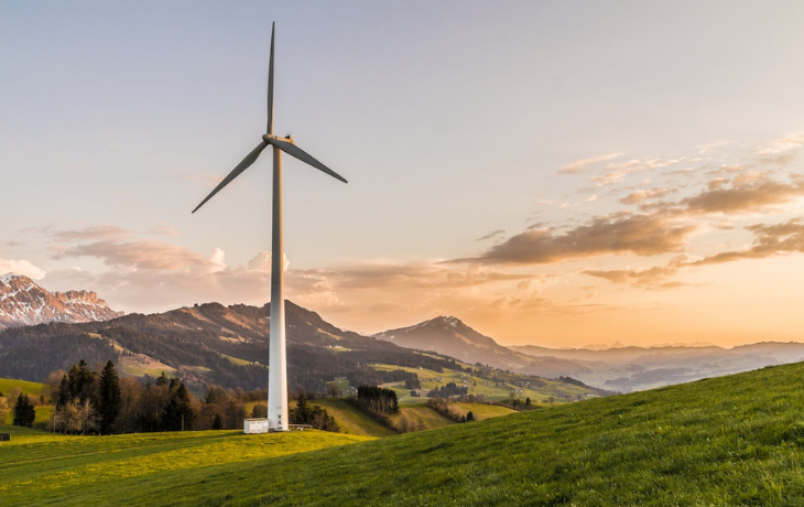 Sunset with large white energy windmill on a remote hilly landscape