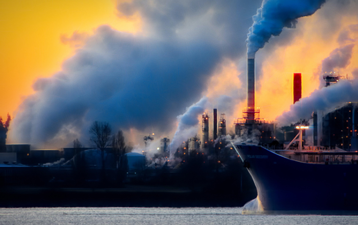 An industrial port with a cargo ship and smokestacks