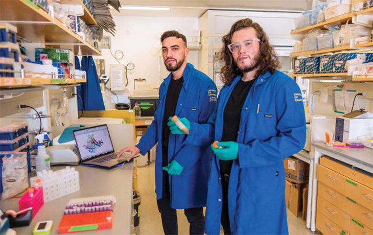2 people in fireproof labcoats working in a lab