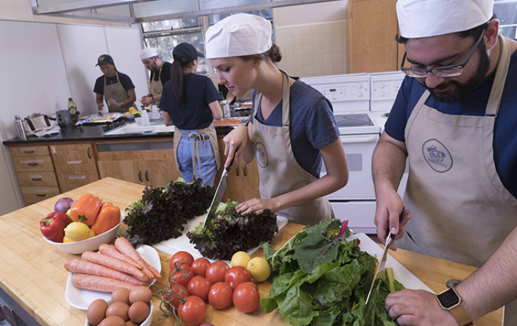Two students cutting vegetables in the teaching kitchen