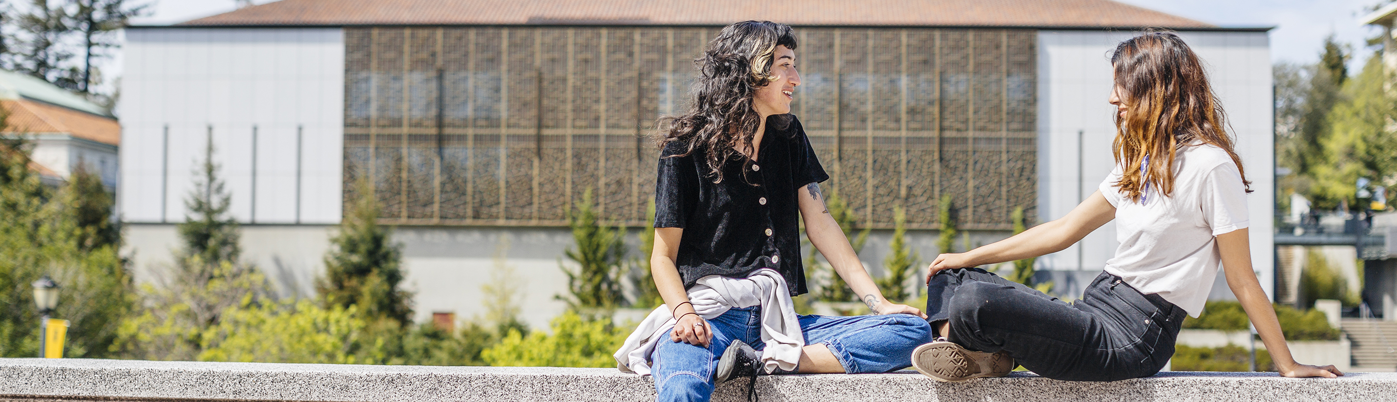 Two students sitting on the balustrade outside Moffitt Library overlooking Memorial Glade on the UC Berkeley campus.