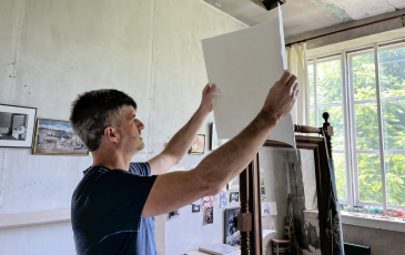 A man holding up a blank canvas